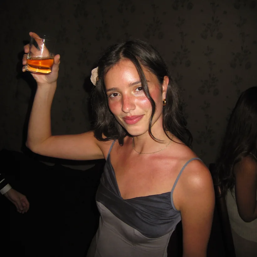 Laura in a satin slip dress raising a glass at a party