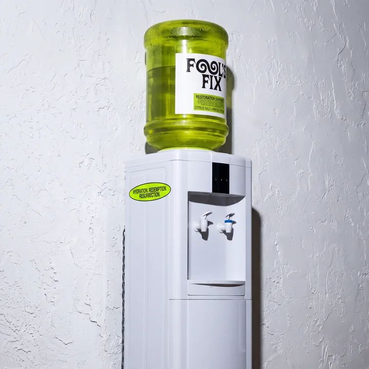 A Fool's Fix water cooler against a white wall